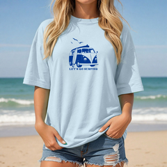 Person wearing a light blue t-shirt with a graphic design on a beach
