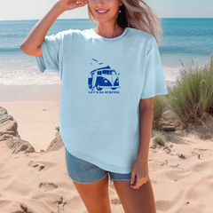 Woman wearing a light blue t-shirt with a graphic design on a beach.