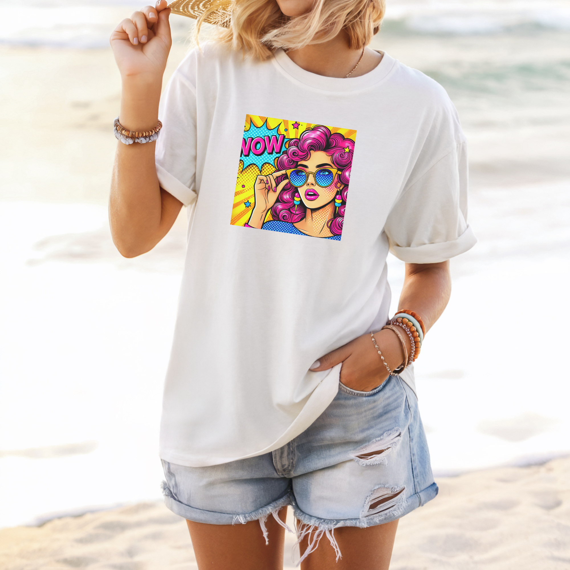 Person wearing a white t-shirt with a colorful graphic on a beach
