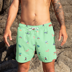 Person wearing green swim shorts with animal prints on a rocky beach.