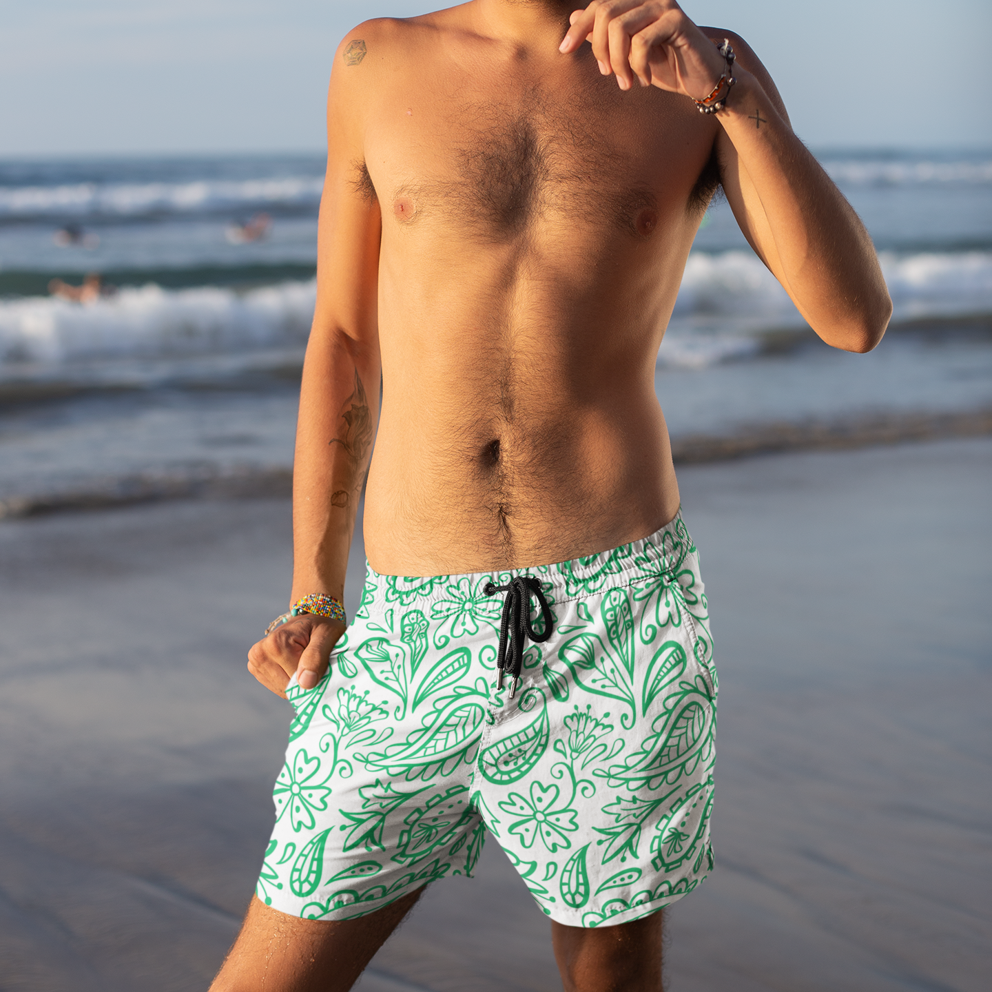 Man wearing green patterned swim shorts on a beach