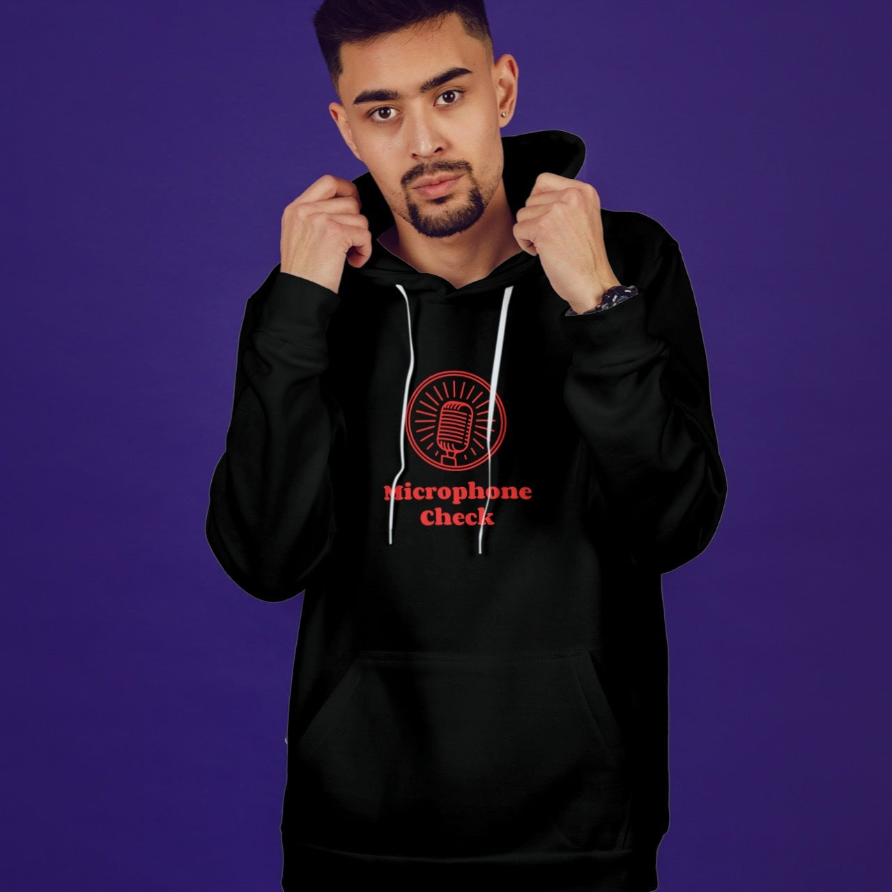 Man wearing a black hoodie with a red logo and text on a purple background
