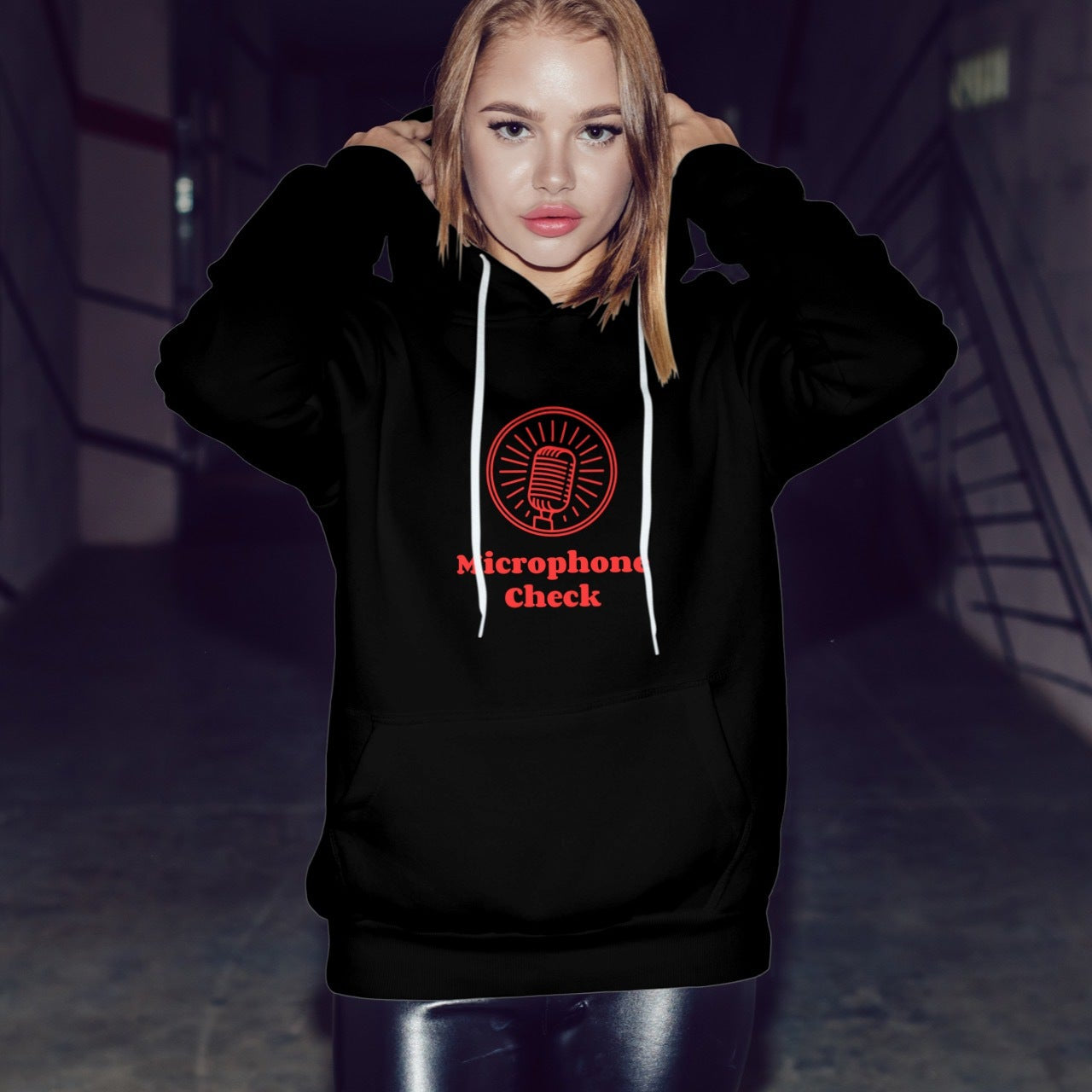 Person wearing a black hoodie with a red logo and text in a dark setting