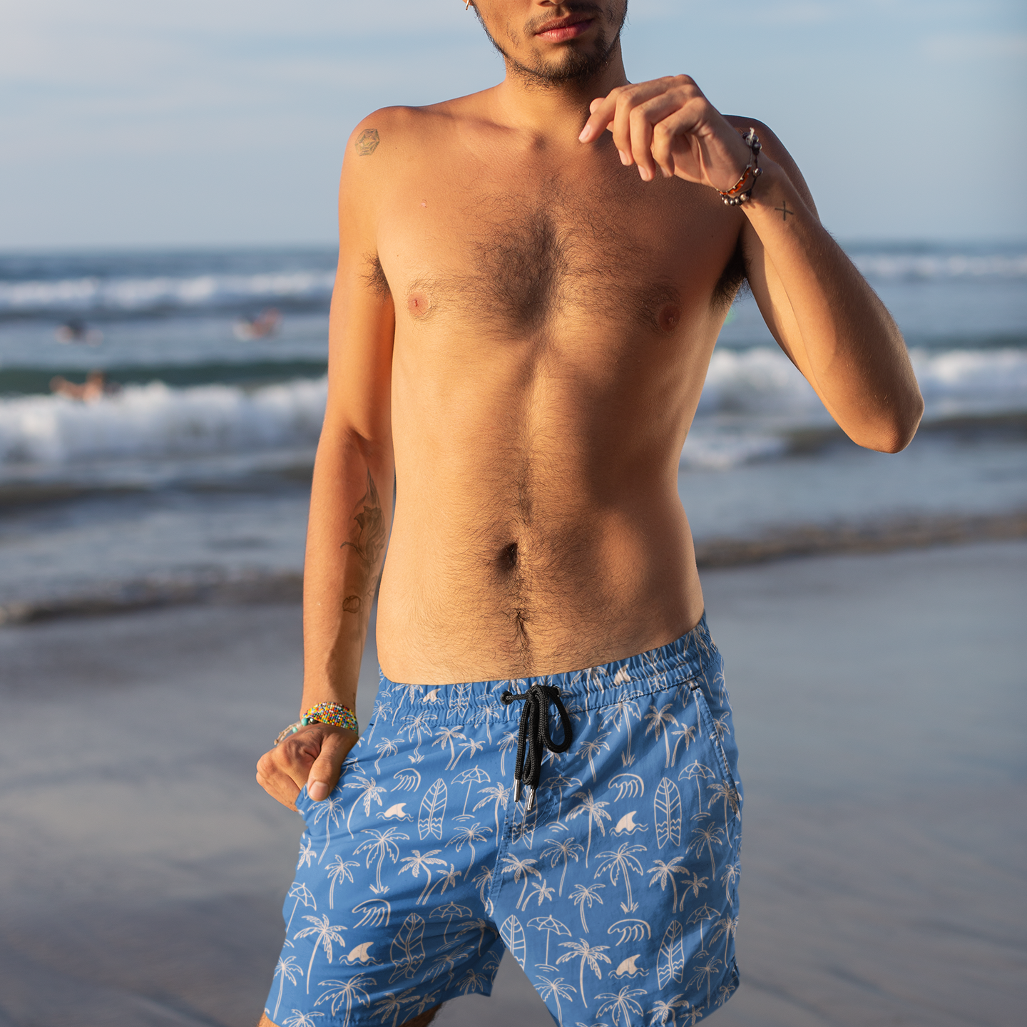 Man wearing blue swim shorts with a beach background