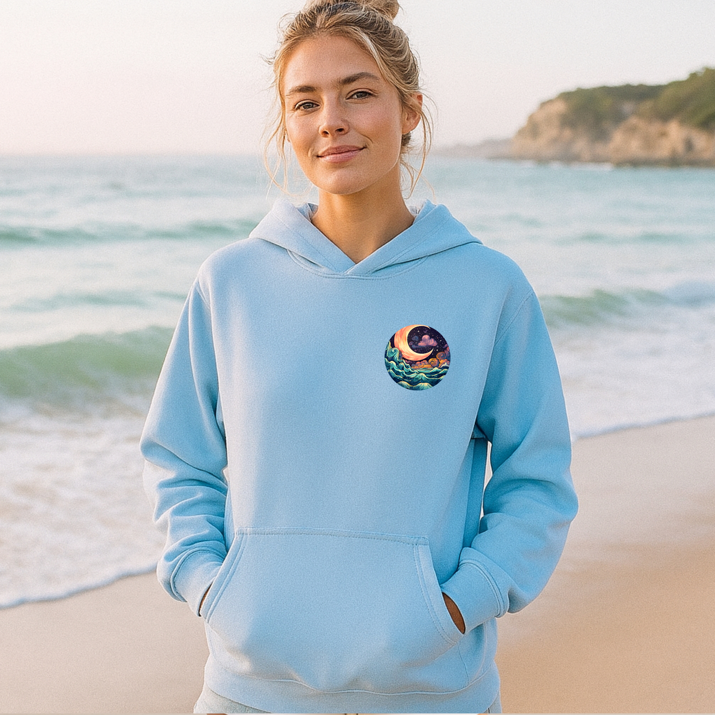 Woman wearing a light blue hoodie with a graphic design on a beach