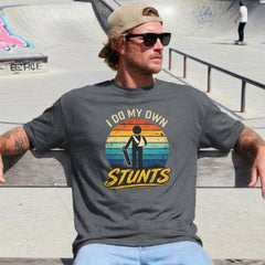 Man wearing a t-shirt with 'Do My Own Stunts' graphic at a skate park.