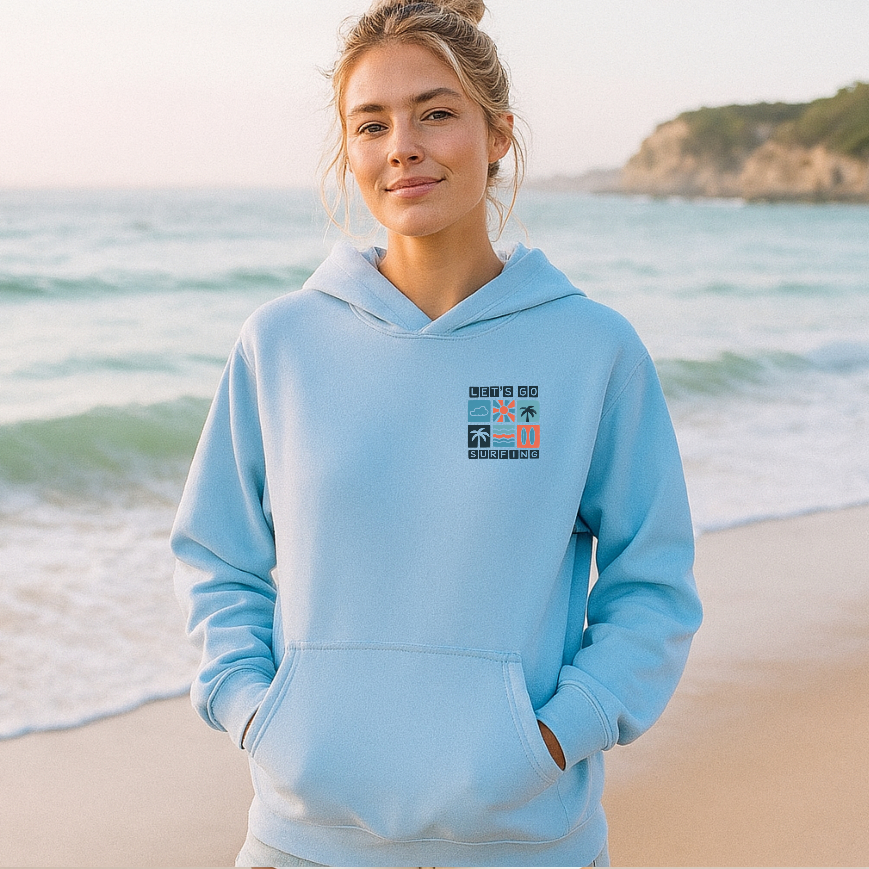 Woman wearing a light blue hoodie with a graphic design on a beach