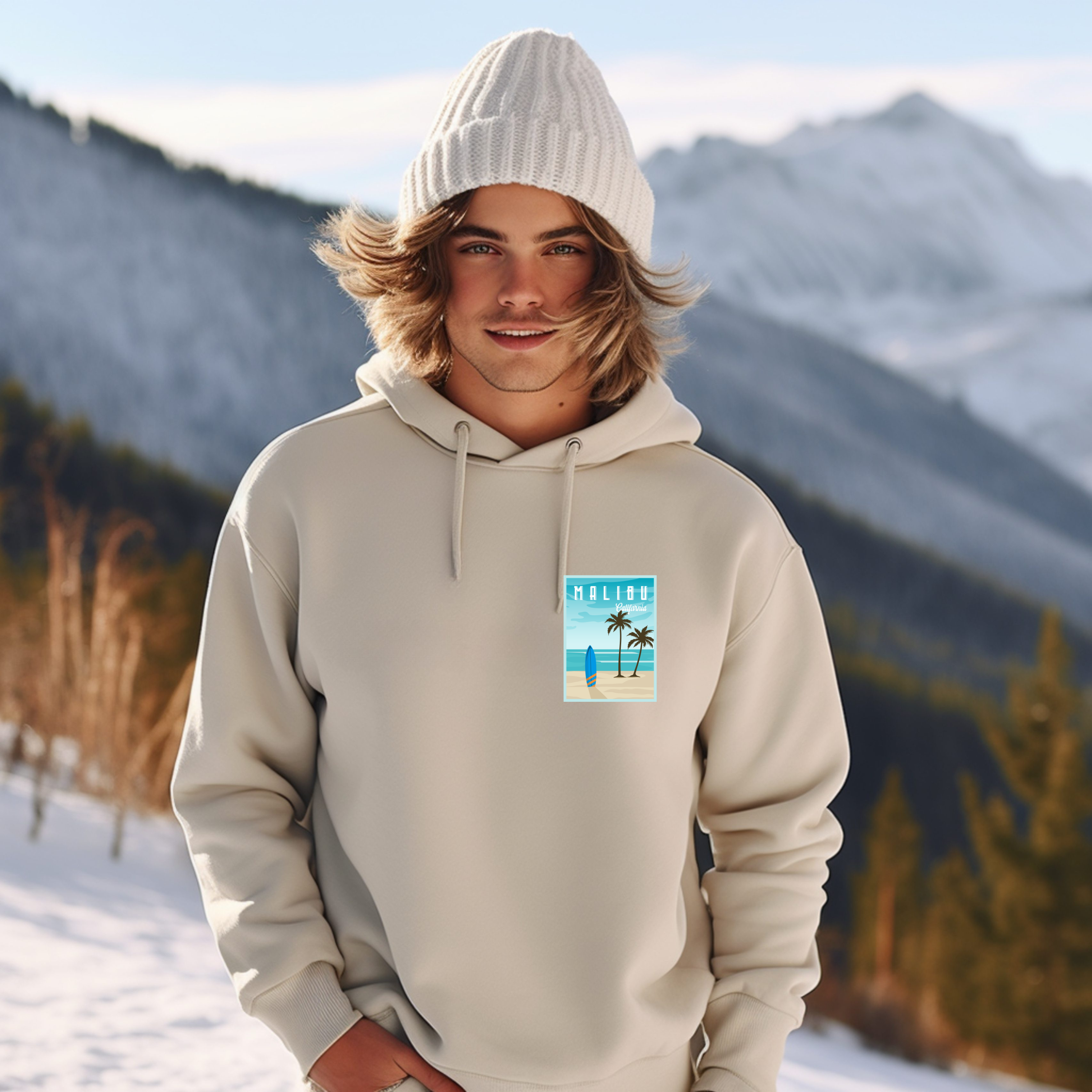 Person wearing a beige hoodie with a beach graphic in a snowy mountain landscape