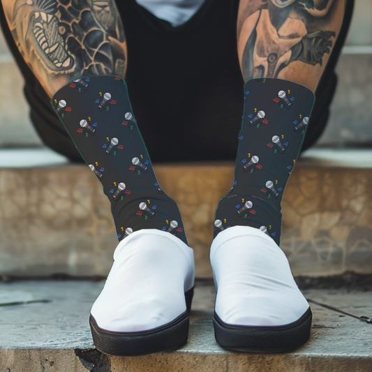 Person wearing black socks with a colorful pattern of microphones and white shoes, sitting on steps.