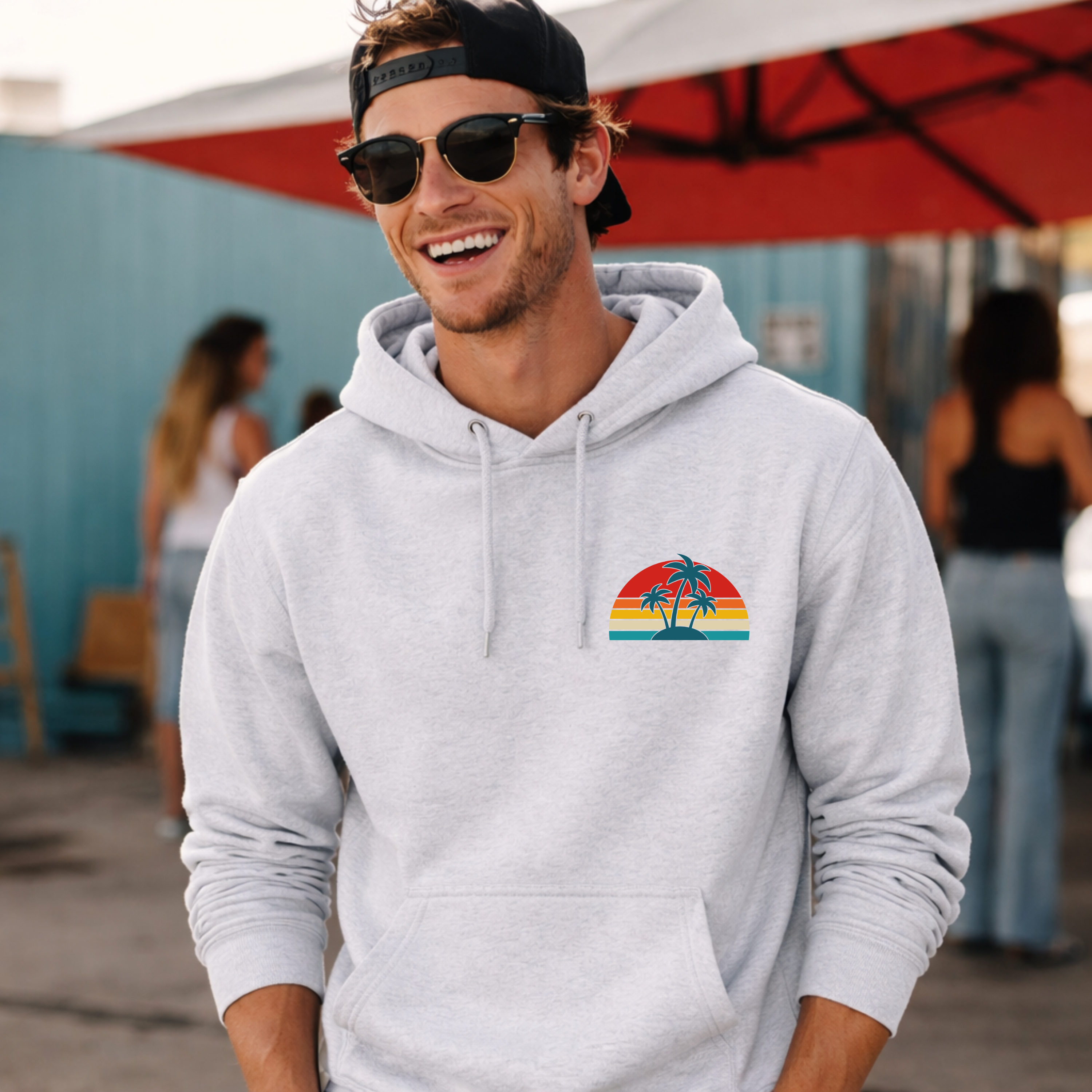 Man wearing a gray hoodie with a colorful graphic, smiling outdoors.