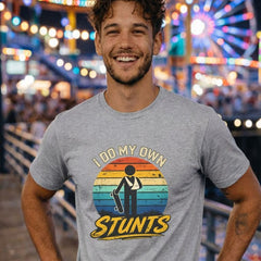 Man wearing a t-shirt with 'Do My Own Stunts' design at an amusement park.