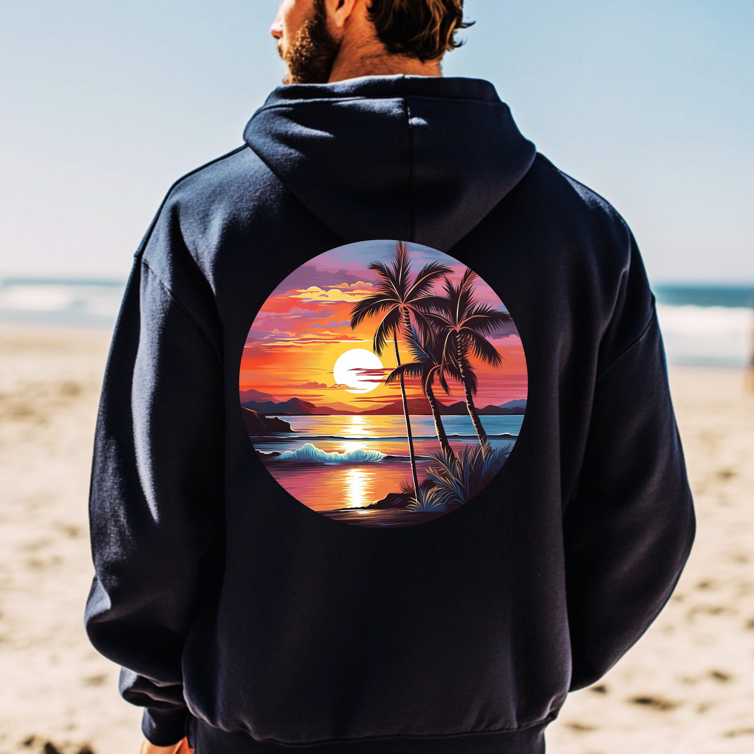Person wearing a black hoodie with a tropical sunset design on a beach