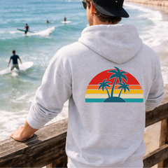 Person wearing a hoodie with a palm tree design by the beach