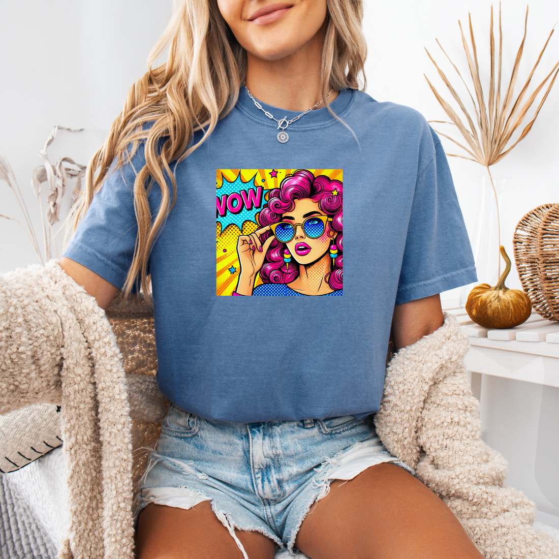 Person wearing a blue t-shirt with a colorful graphic design sitting on a couch.
