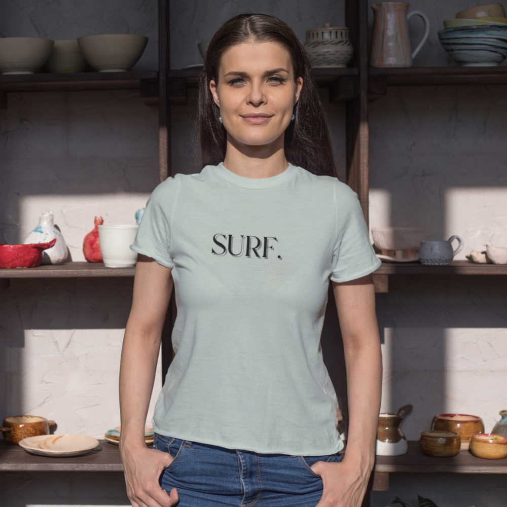 A woman wearing a Bay Green shirt that says, "SURF"