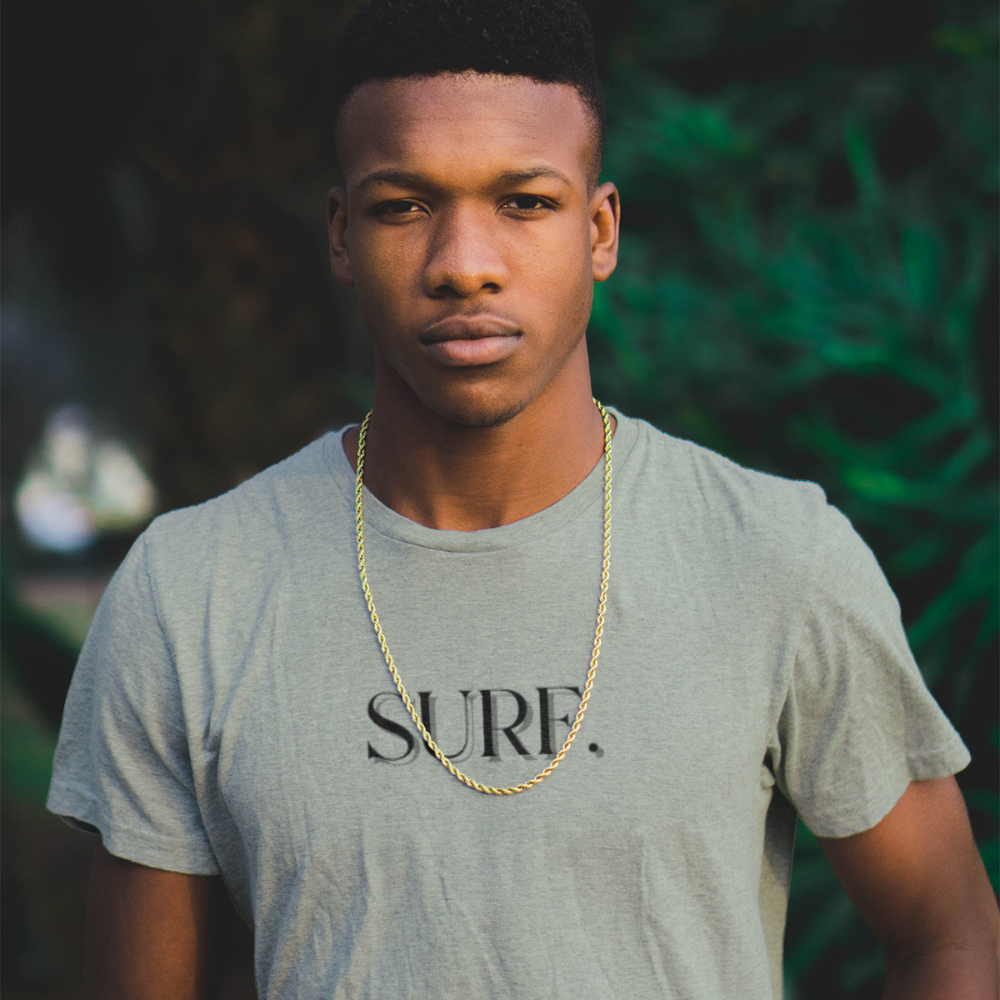Man wearing a gray t-shirt with 'SURF.' text and a gold chain, standing outdoors.