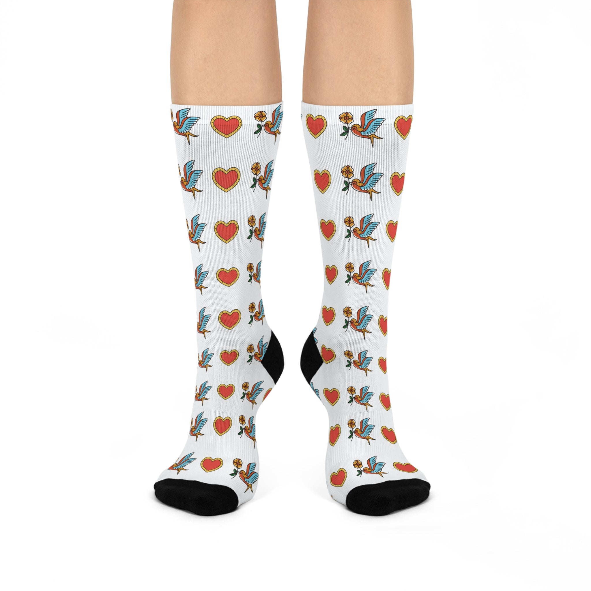 White socks with colorful heart and bird pattern worn by a person on a white background