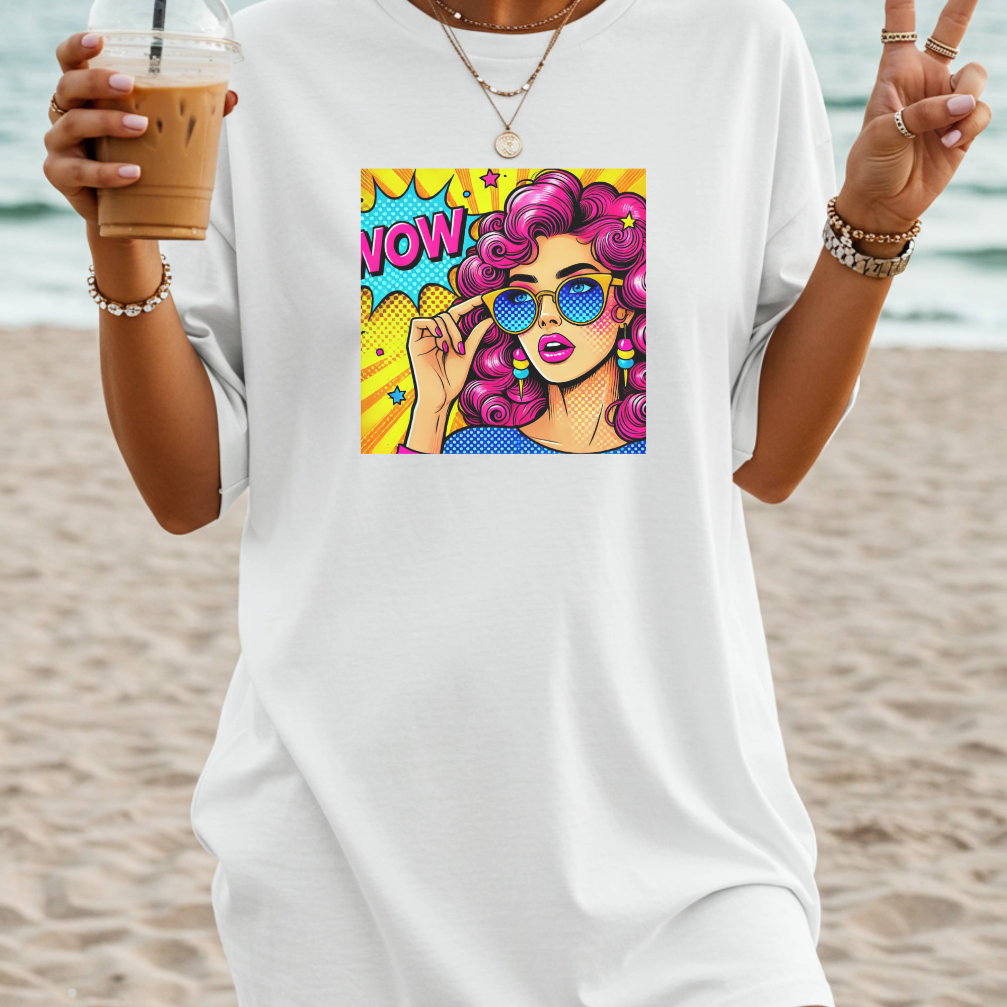Person wearing a white t-shirt with a colorful graphic design on a beach.