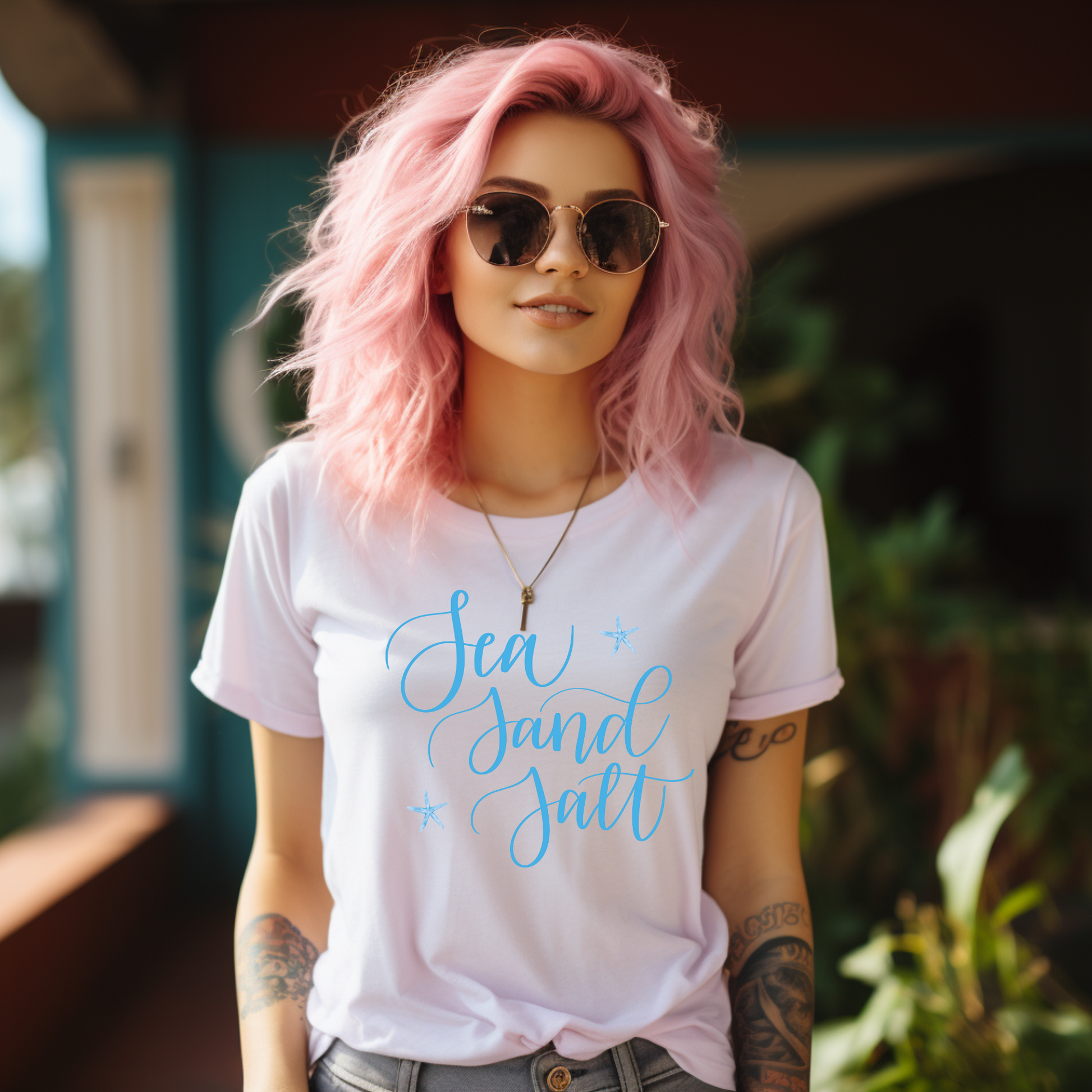 Woman with pink hair wearing a white t-shirt with 'Sea Sand Salt' text.