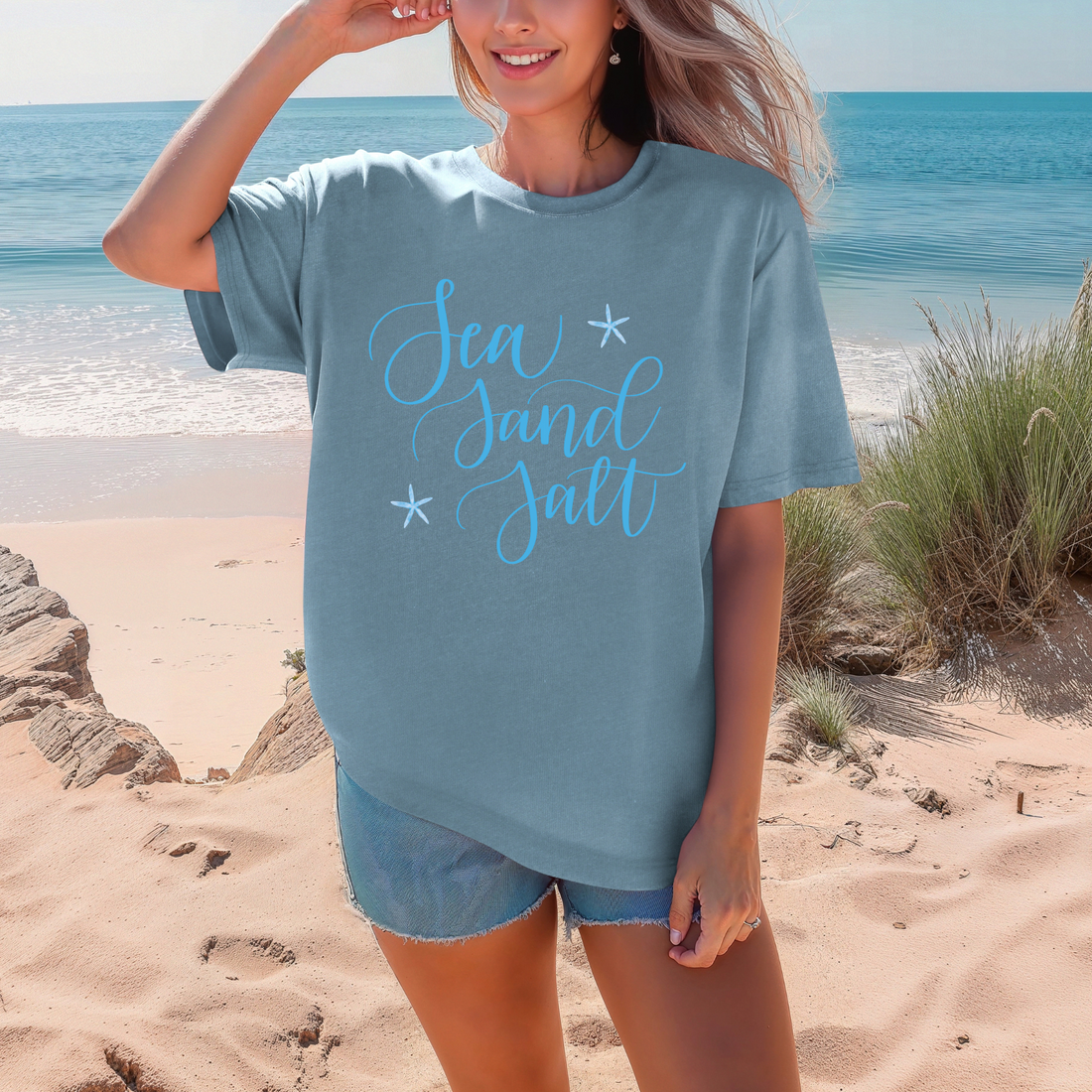 Person wearing a cream-colored sweatshirt with 'Sea Sand Salt' text in blue, sitting on a wooden floor.