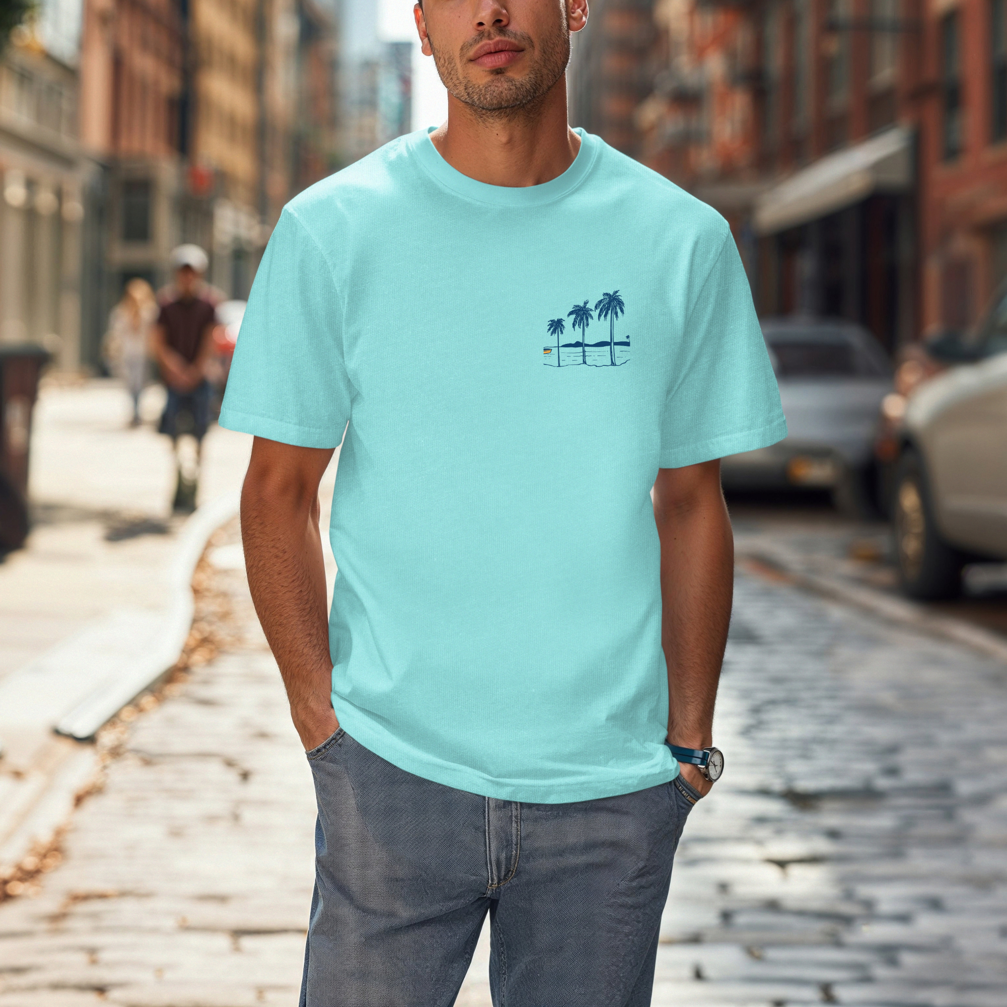 Man wearing a light blue t-shirt with palm tree design on a city street.