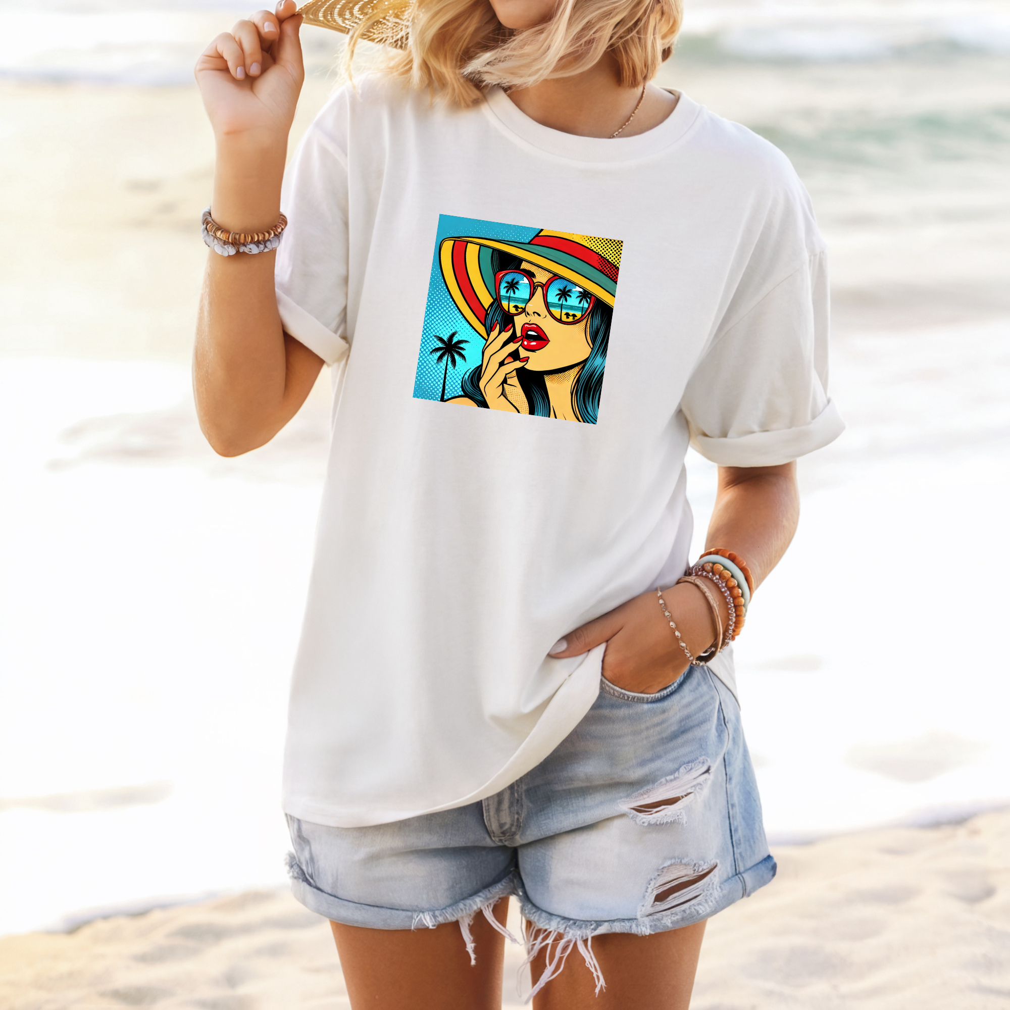 Woman wearing a white t-shirt with a colorful graphic design on a beach.