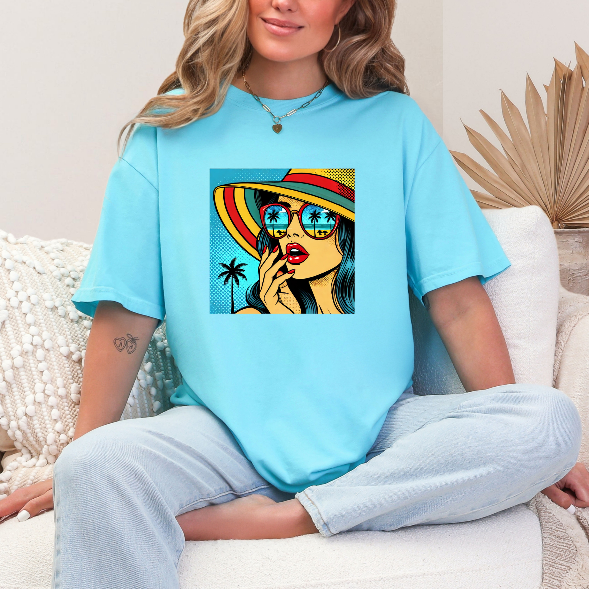 Person wearing a light blue t-shirt with a colorful graphic design sitting on a white couch.