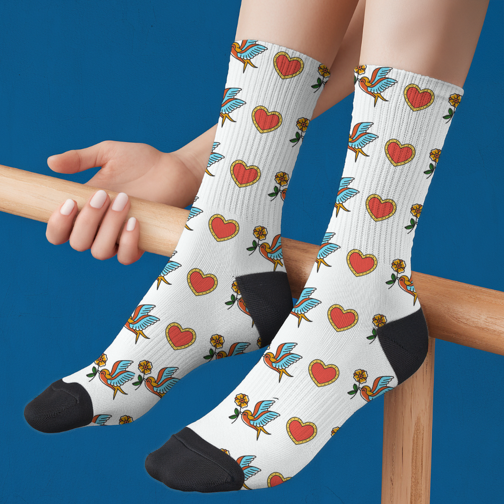 White socks with colorful heart and bird pattern worn by a person against a blue background