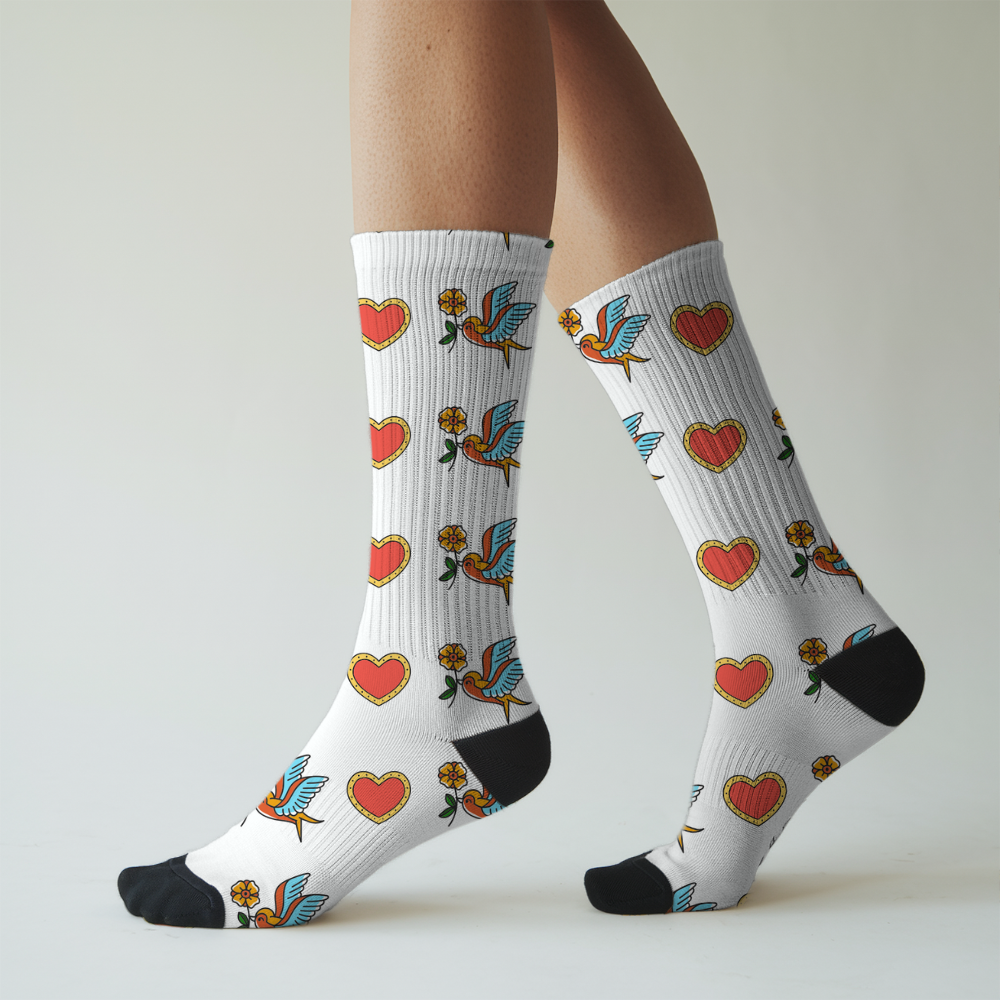White socks with heart and flower patterns worn by a person on a light gray background