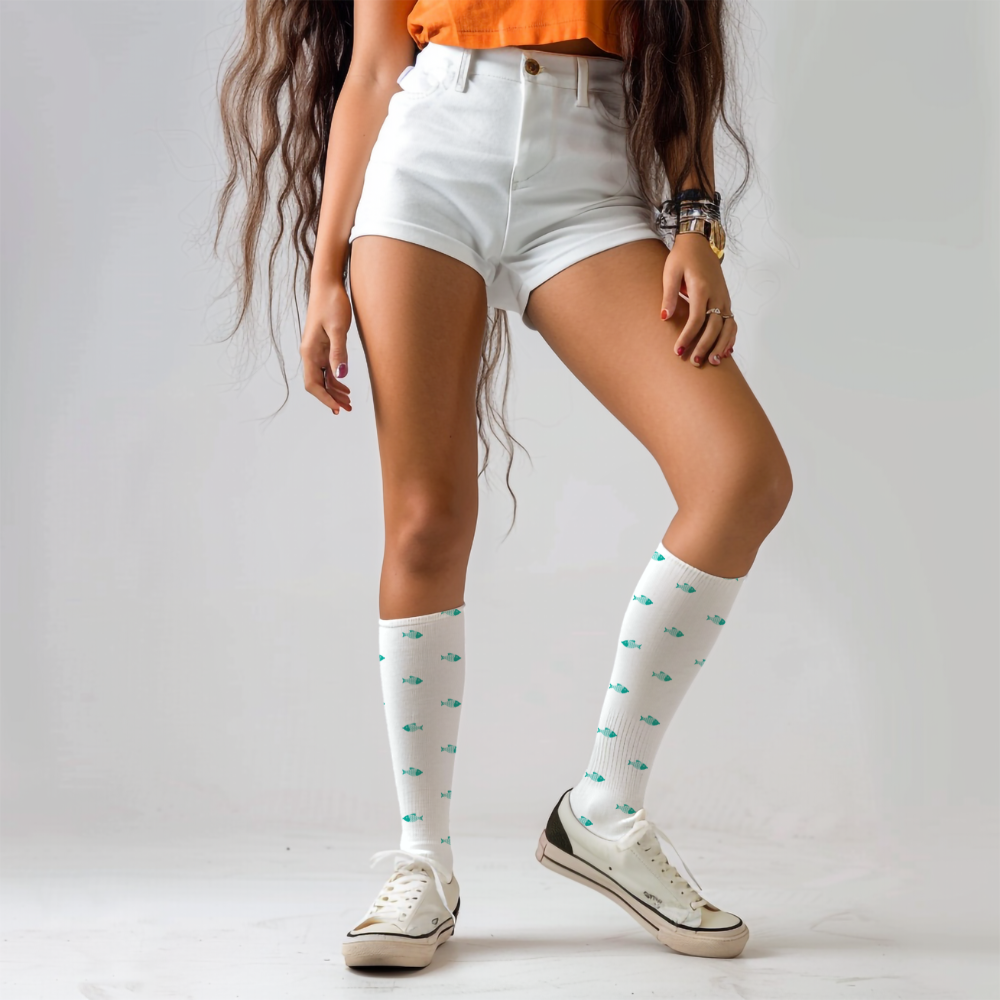 Person wearing white knee-high socks with green patterns and white sneakers on a plain background