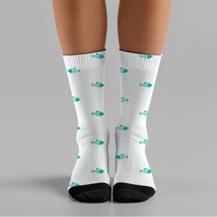 White socks with blue fish pattern worn by a person on a gray background