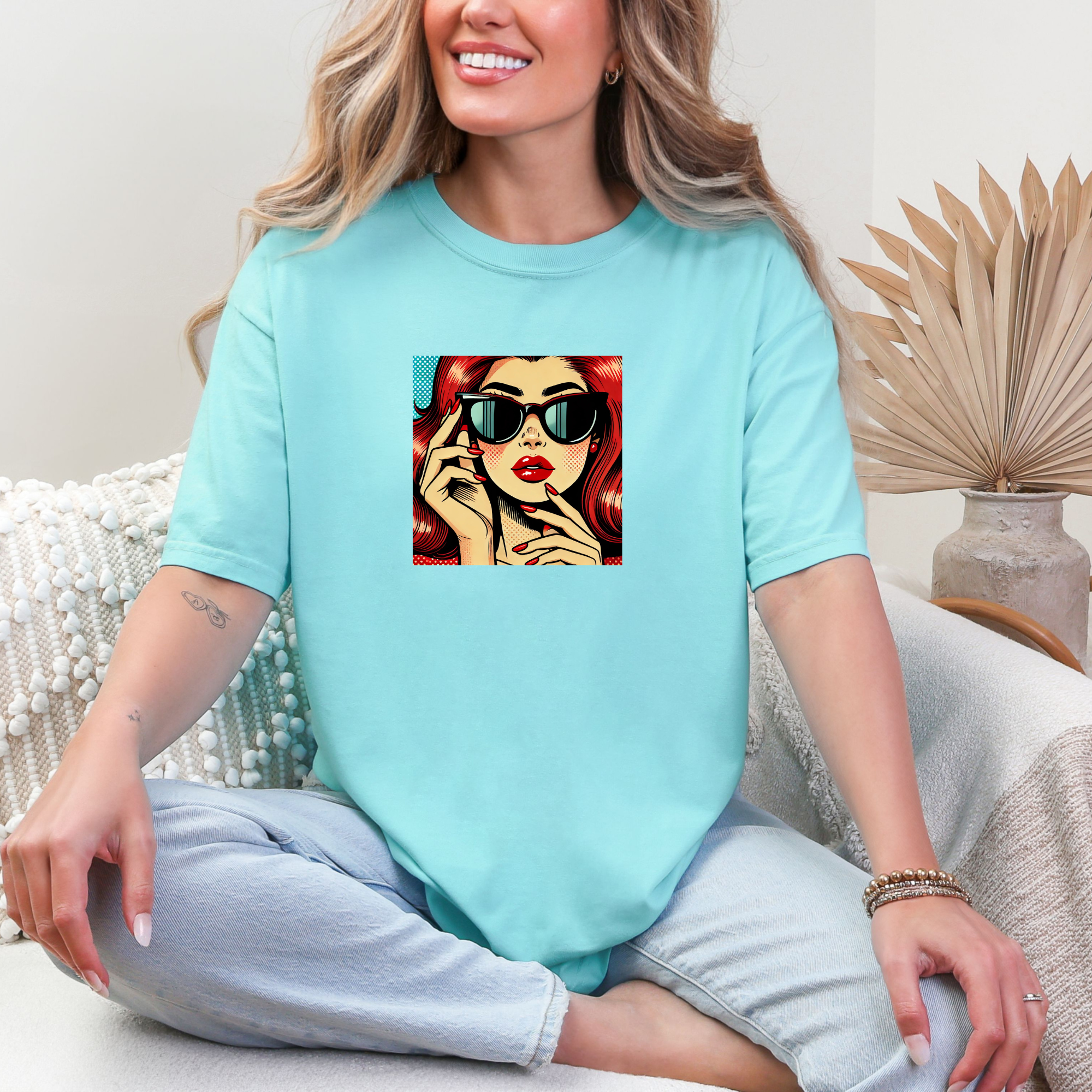 Woman wearing a light blue t-shirt with a colorful graphic design of a woman on it.