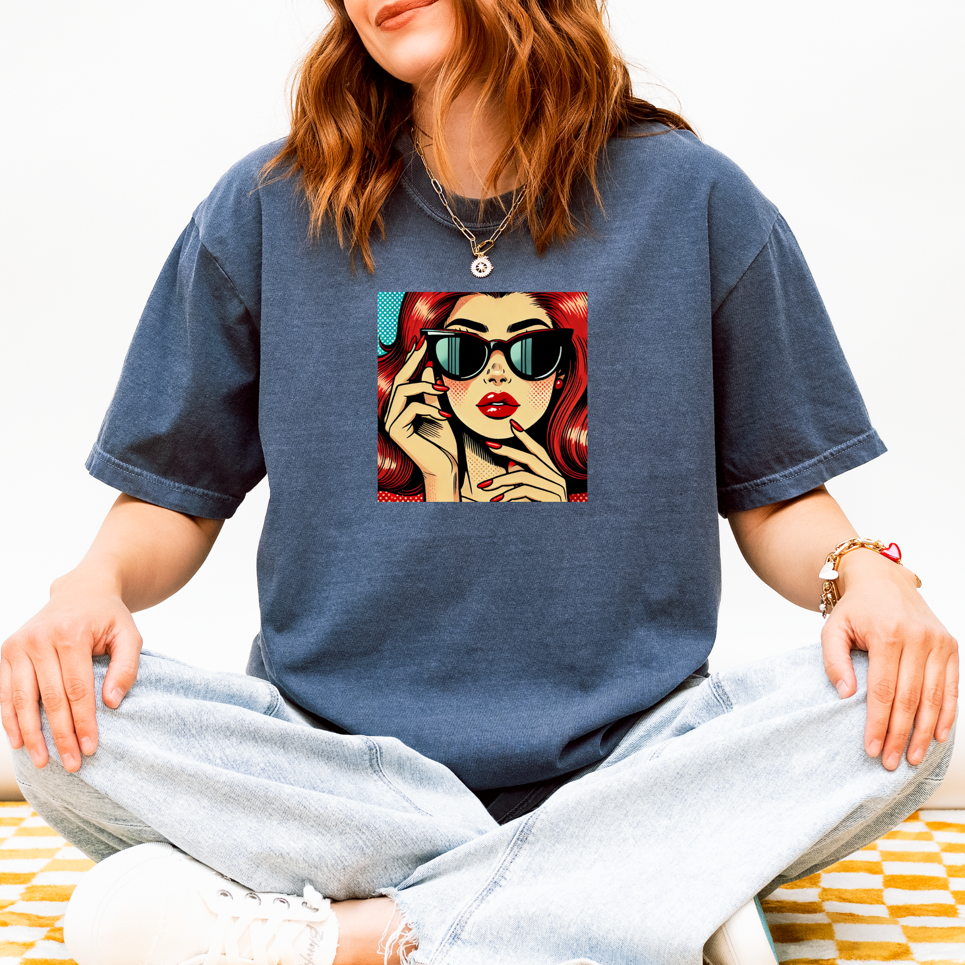 Person wearing a blue t-shirt with a graphic design of a woman with red hair and sunglasses.