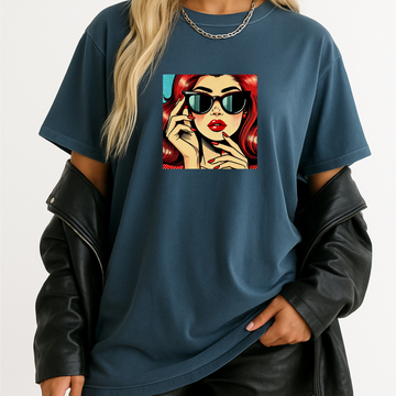 Person wearing a blue t-shirt with a graphic design of a woman with red hair and sunglasses.