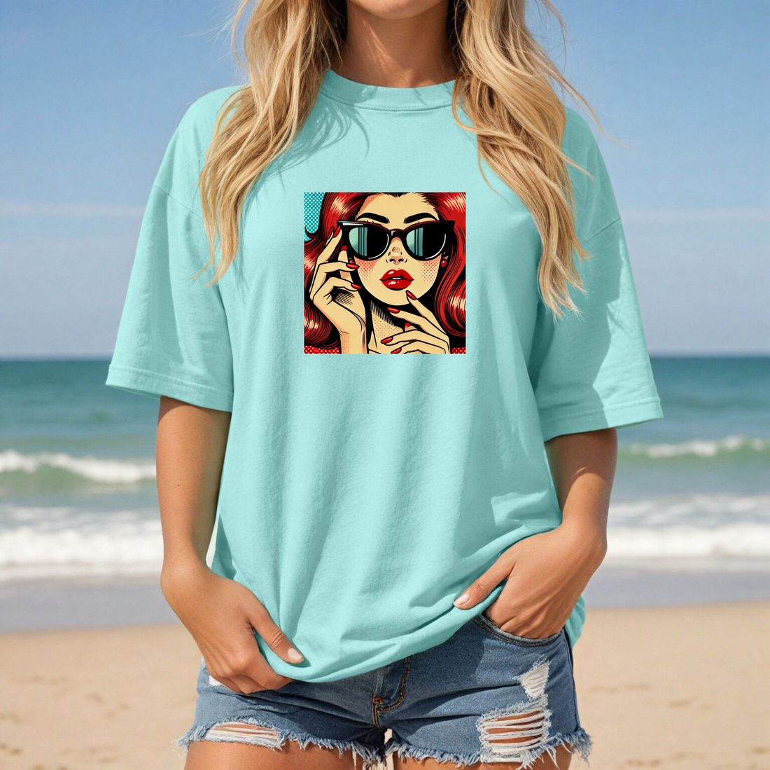 Person wearing a blue t-shirt with a graphic design of a woman with red hair and sunglasses.