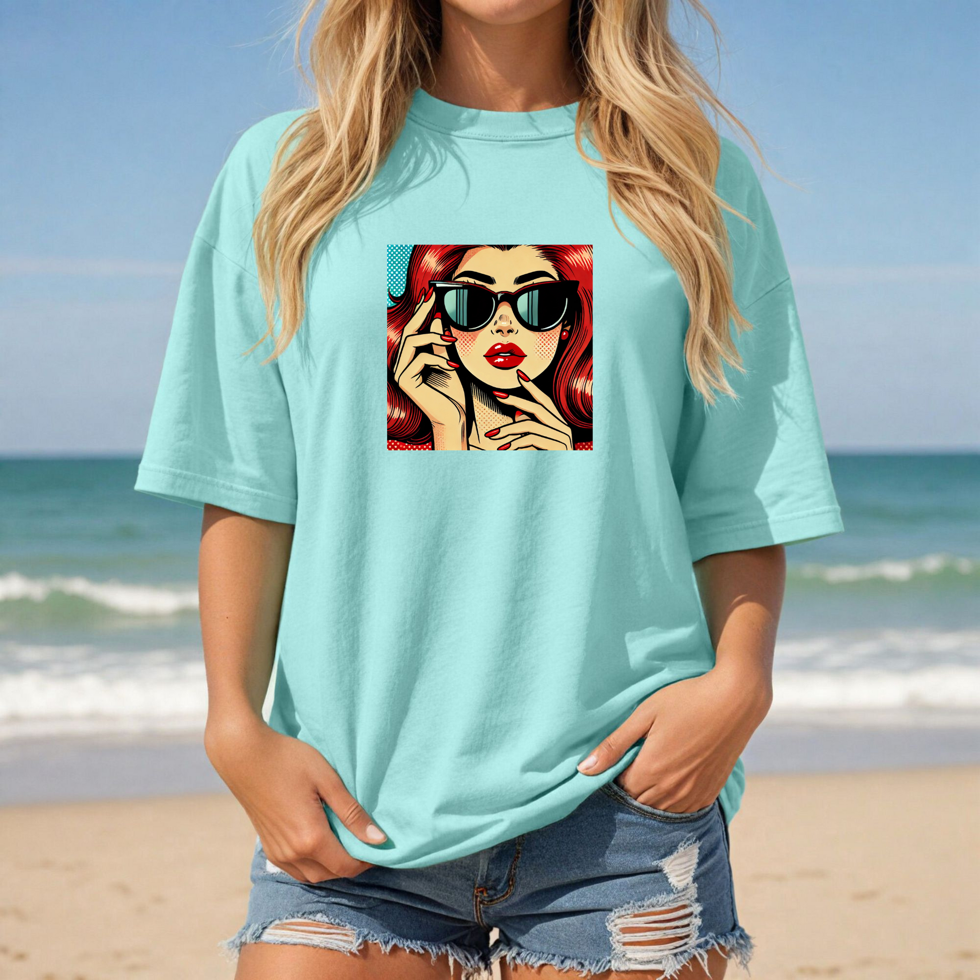 Person wearing a light blue t-shirt with a graphic design on a beach