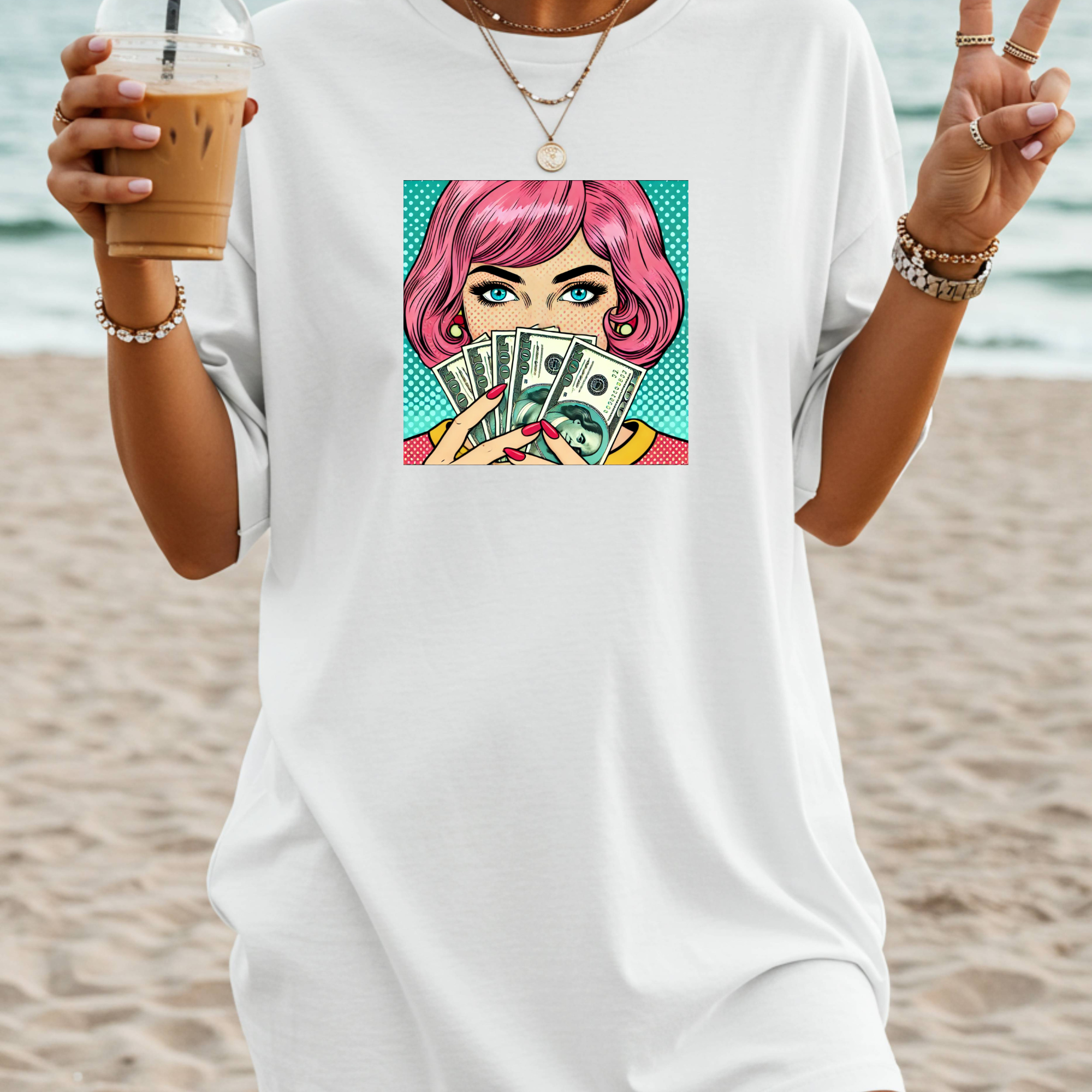 Person wearing a white t-shirt with a graphic of a woman with pink hair holding money, standing on a beach.