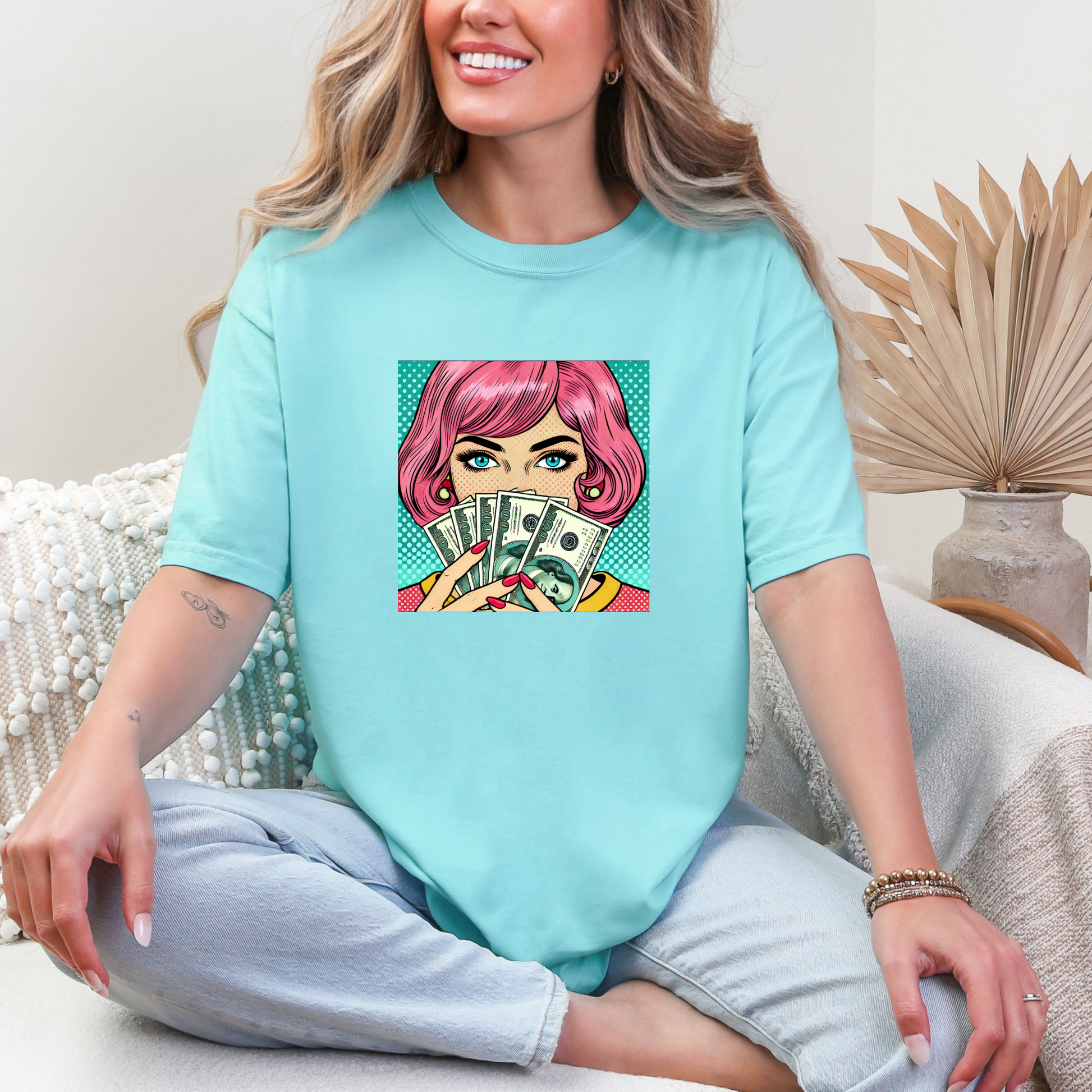 Woman wearing a light blue t-shirt with a graphic design of a character holding money.