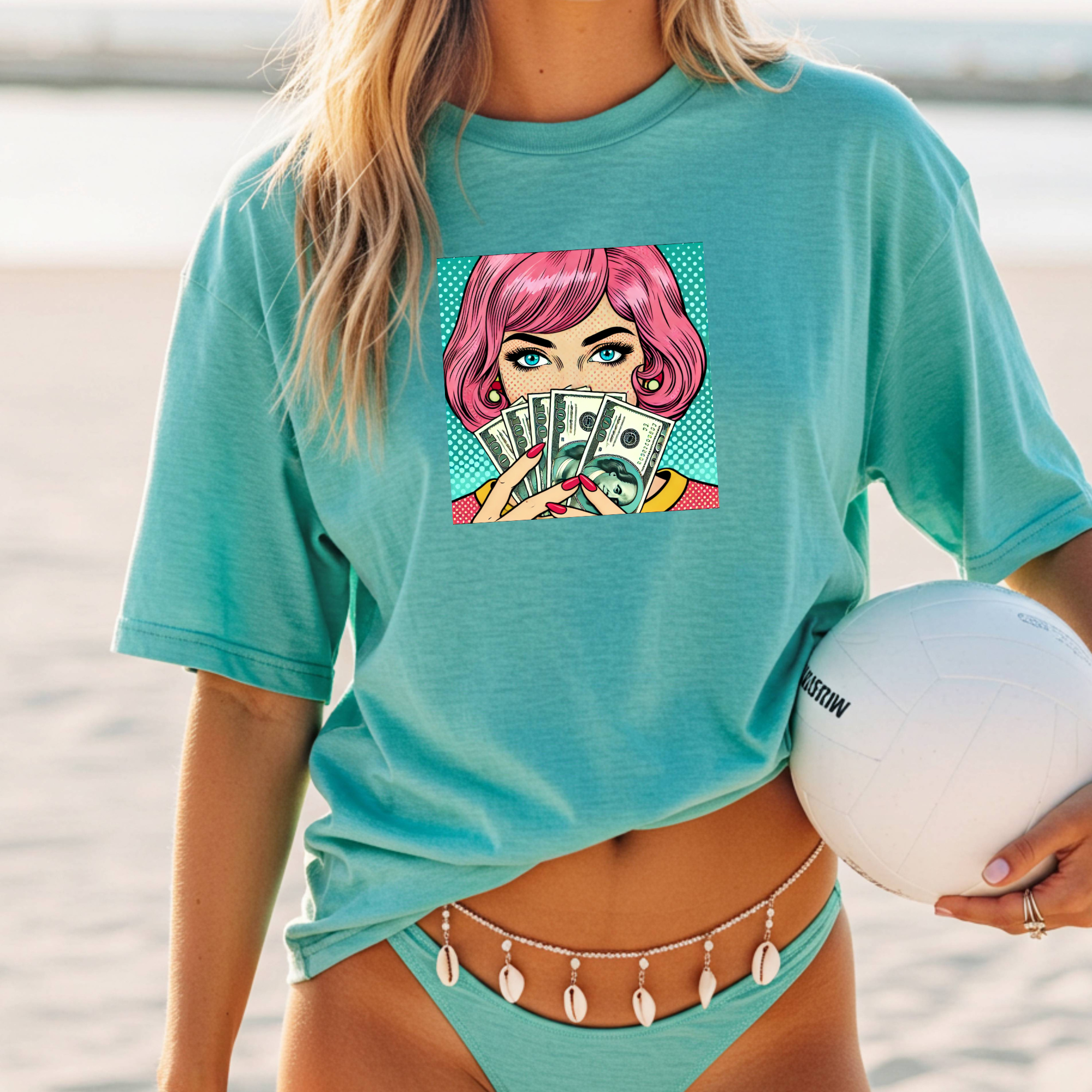 Person wearing a teal t-shirt with a graphic design on a beach