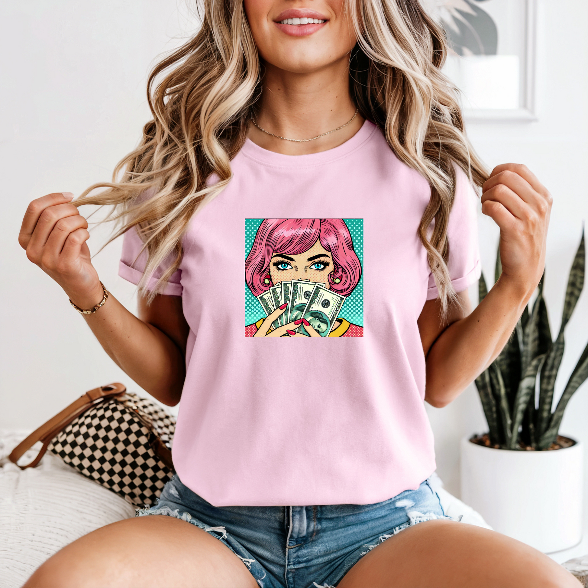 Woman wearing a pink t-shirt with a graphic design of a woman with pink hair holding money.