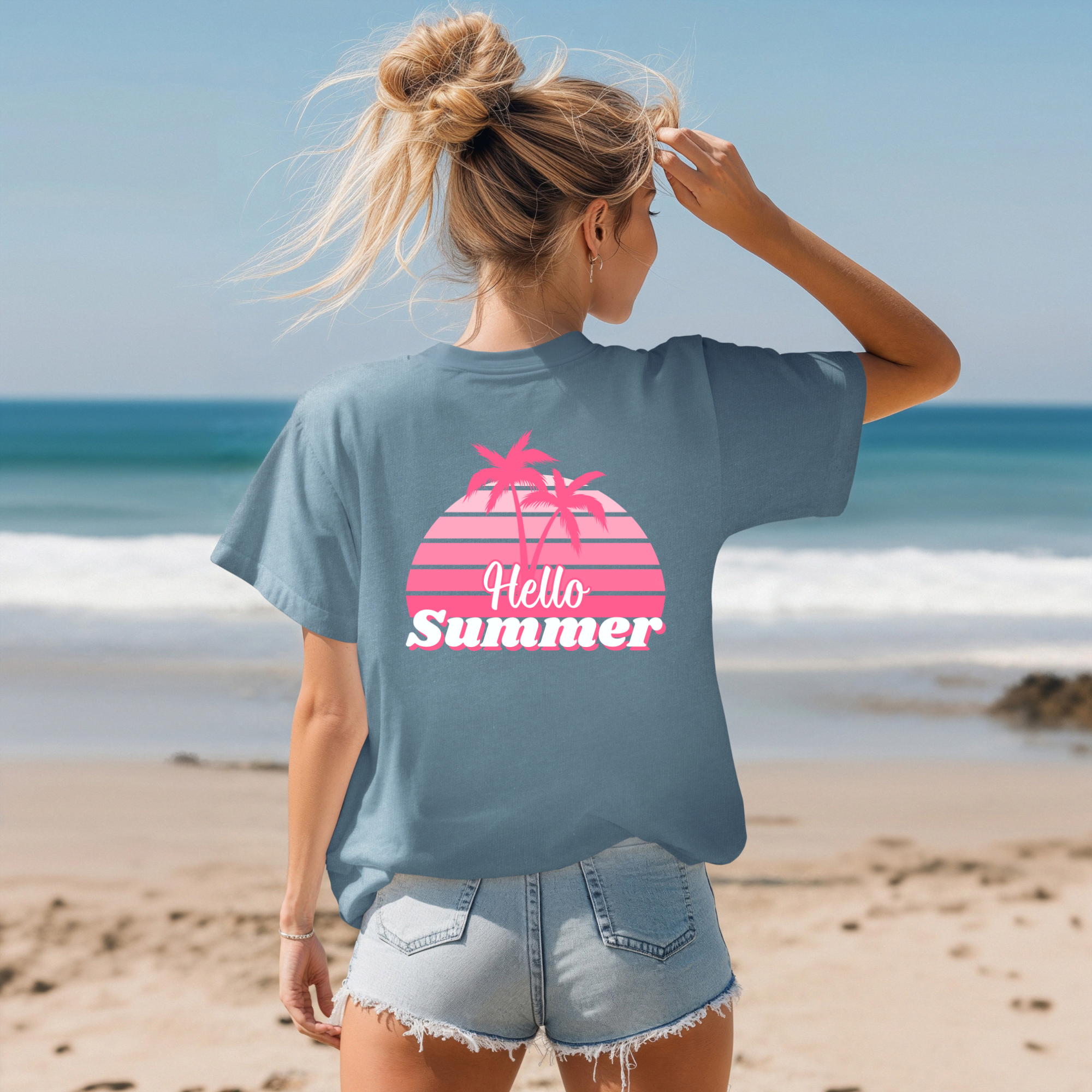 Woman on a beach wearing a blue t-shirt with 'Hello Summer' design.
