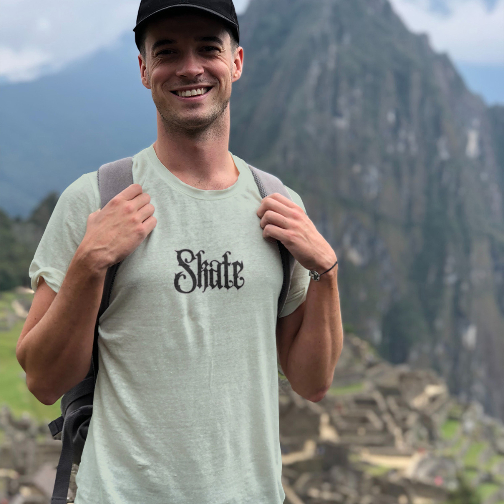 Man wearing a 'Shirt' t-shirt with a scenic mountain background