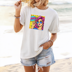 Person wearing a white t-shirt with a colorful graphic on a beach