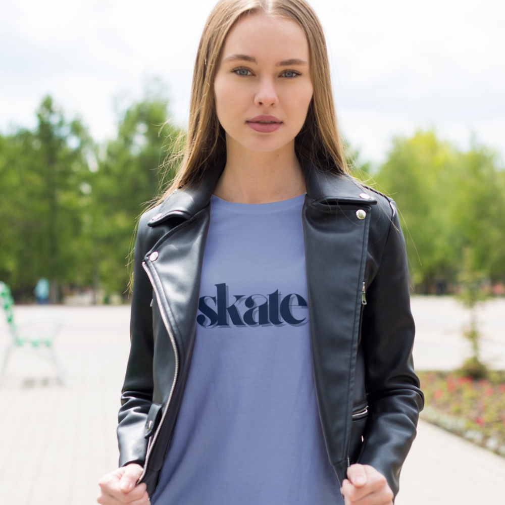 Woman wearing a black leather jacket over a blue t-shirt with 'skate' text, standing outdoors.