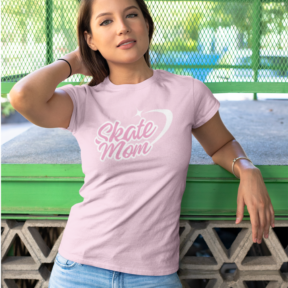 Woman wearing a pink 'Skate Mom' t-shirt leaning against a green metal structure.