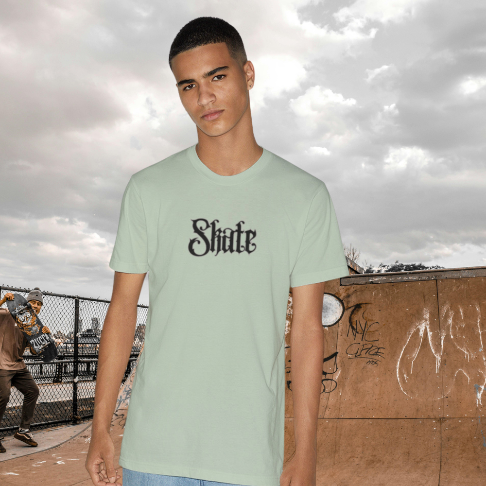 Man wearing a light green t-shirt with 'Shite' printed on it against a gray background