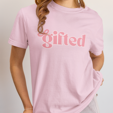 Person wearing a pink t-shirt with 'gifted' text on a plain background