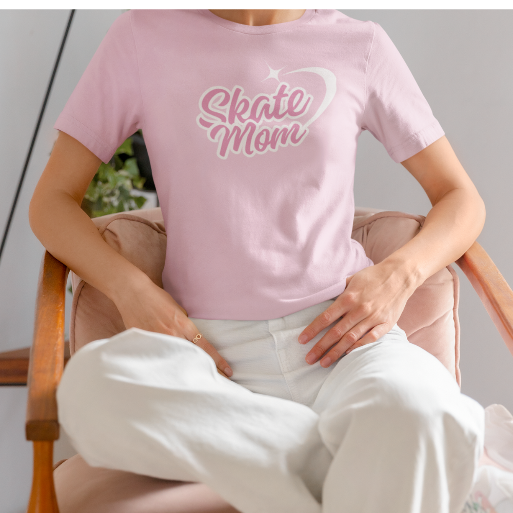 Person wearing a pink t-shirt with 'Skate Mom' text sitting on a chair.