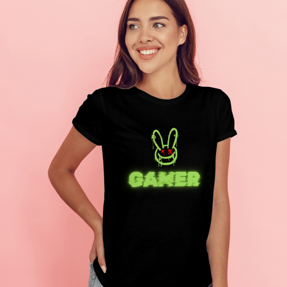 Woman wearing a black t-shirt with a green graphic and 'Gamer' text on a pink background