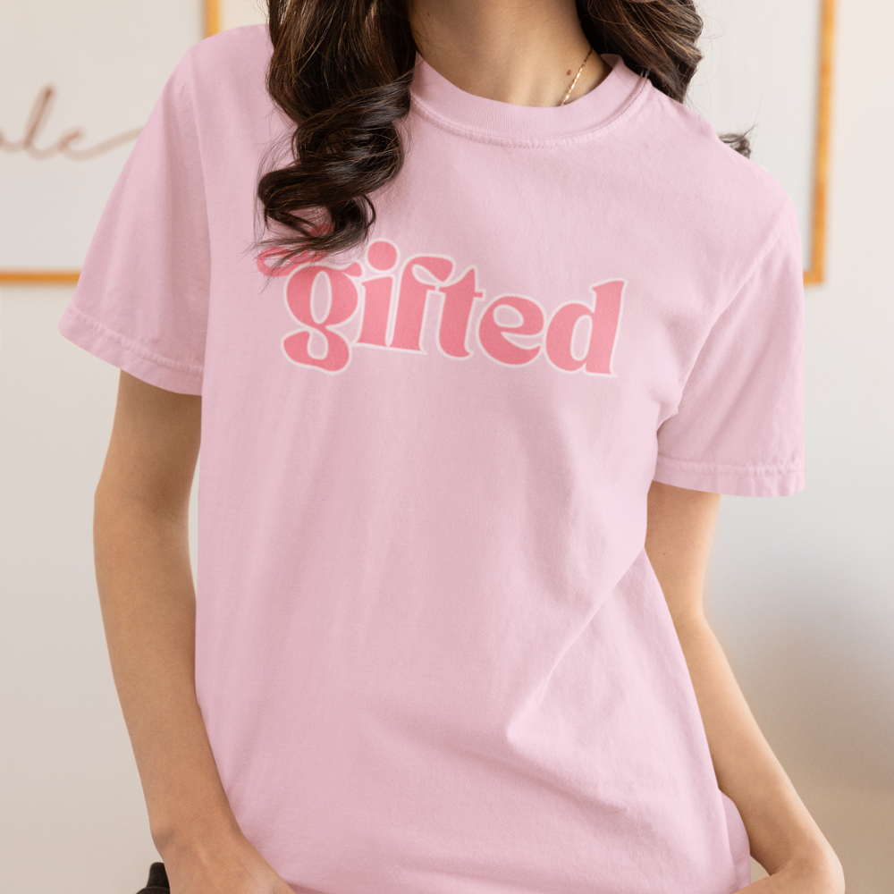 Person wearing a pink t-shirt with 'gifted' text on a plain background